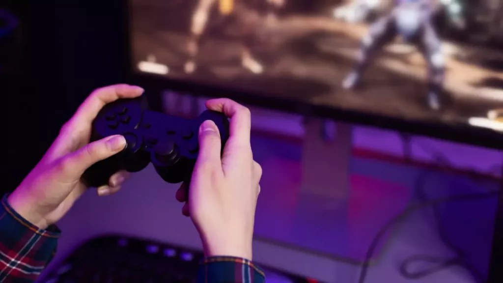 Mãos masculinas segurando controle para pc em frente de monitor