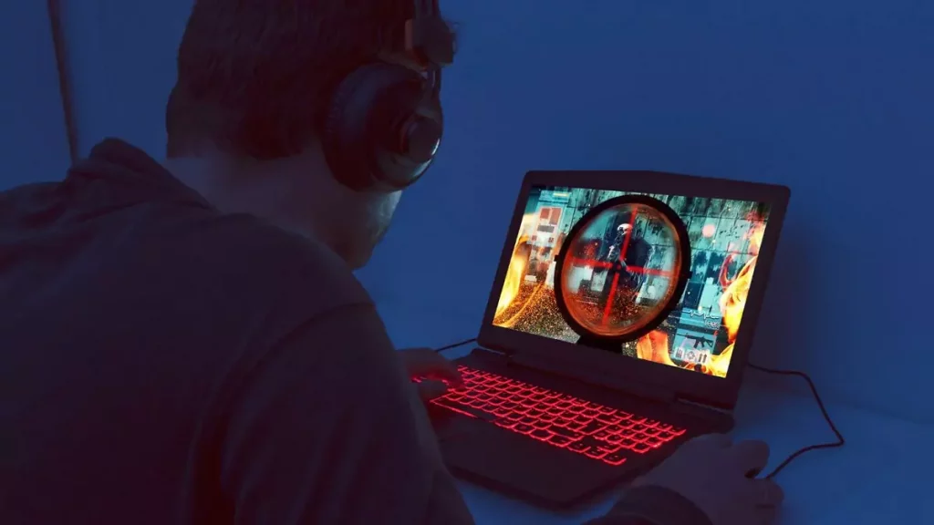 Homem jogando com notebook gamer em sala escura